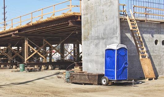 blue porta potties arranged in a neat line on a job site